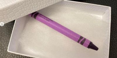 a purple crayon in a white gift box