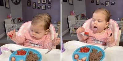 baby in a highchair eating with a spoon and fork