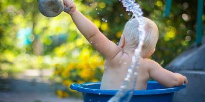 Baby splashing in bucket outside