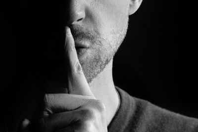 man holding finger to his mouth as a signal to be quiet