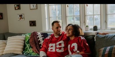 dad and daughter in football jerseys snuggled up on the sofa