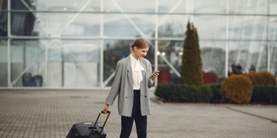 woman on phone pulling luggage