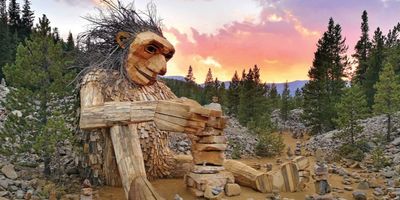 Giant wooden troll sitting on the ground building rock towers