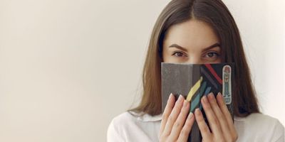 woman hiding her mouth with a book