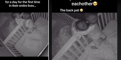 twin babies hugging over the side of their cribs
