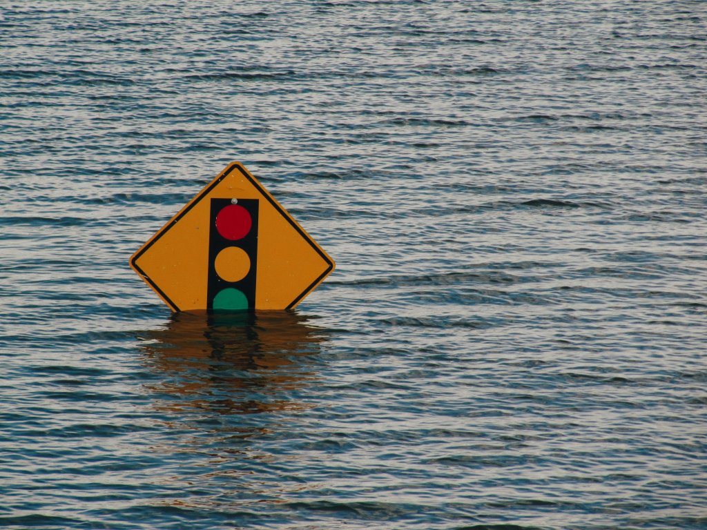Traffic light sign partially submerged in water.