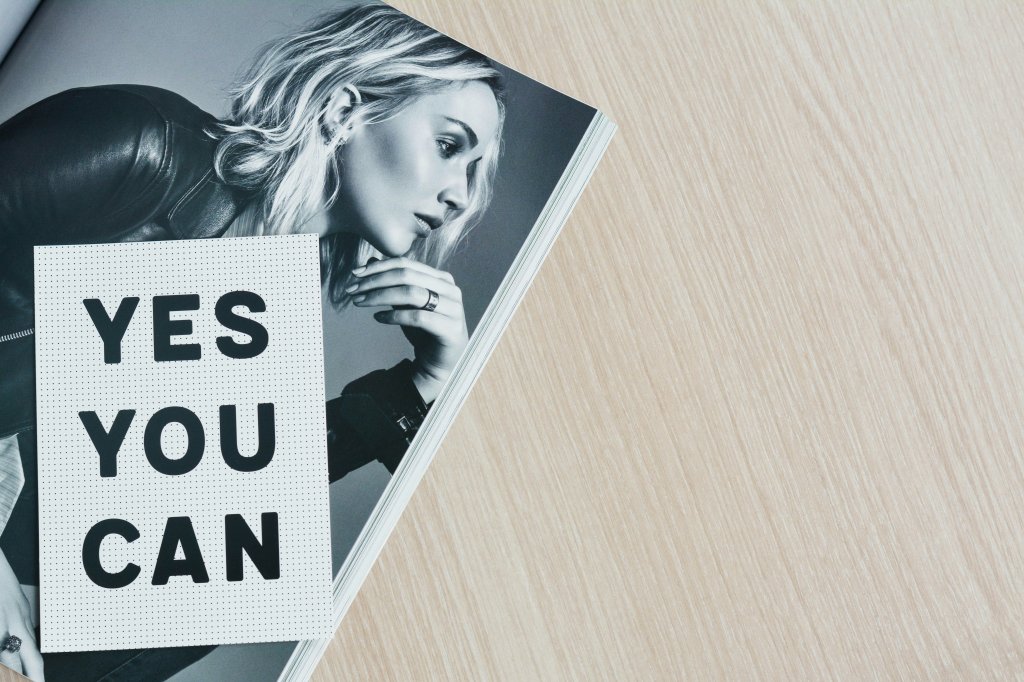 Jennifer Lawrence in a magazine with "YES YOU CAN" text on wooden table.