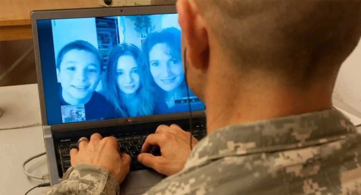 Soldier in uniform video chatting with family on a laptop screen.