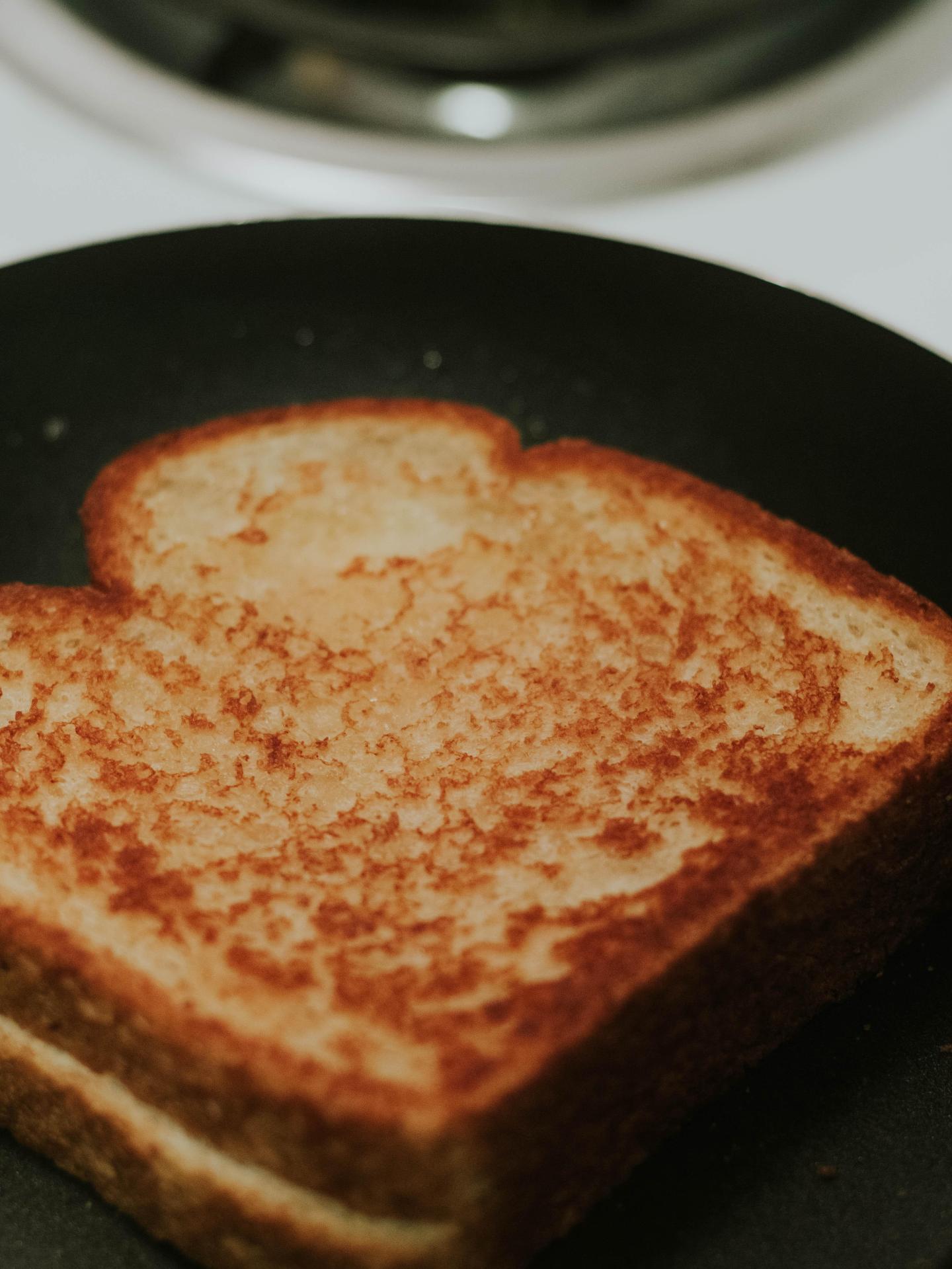 A grilled cheese in a frying pan all done.