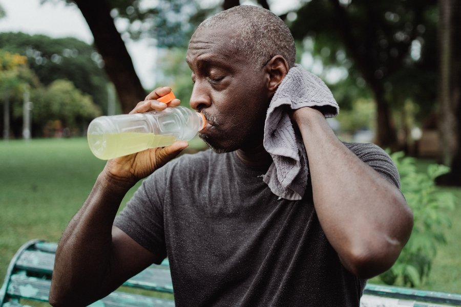 man sweating and drinking a sports drink