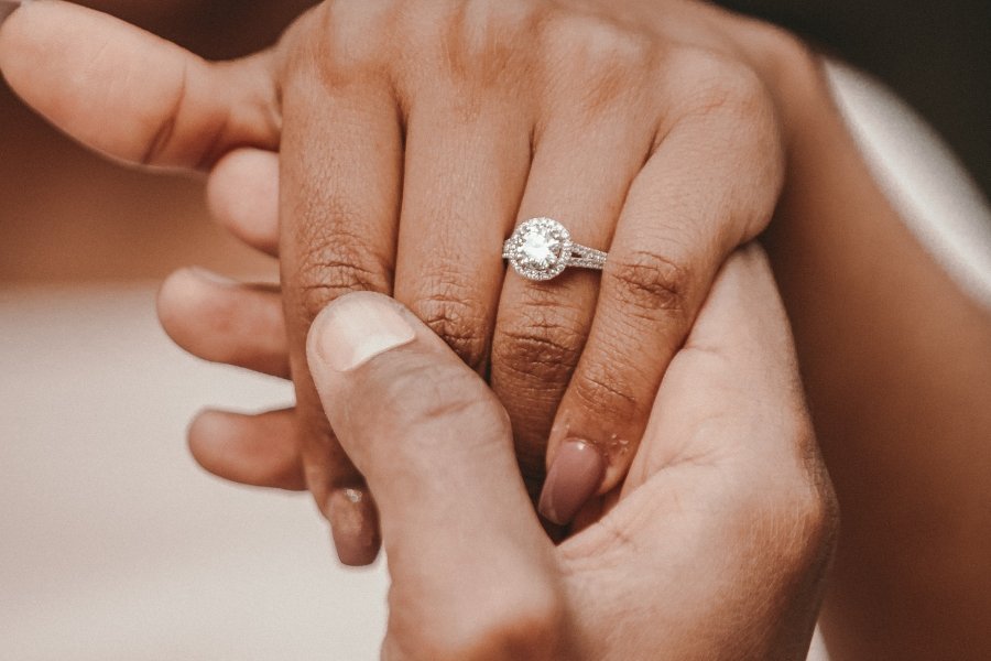 man holding woman's hand wearing a band on her ring finger
