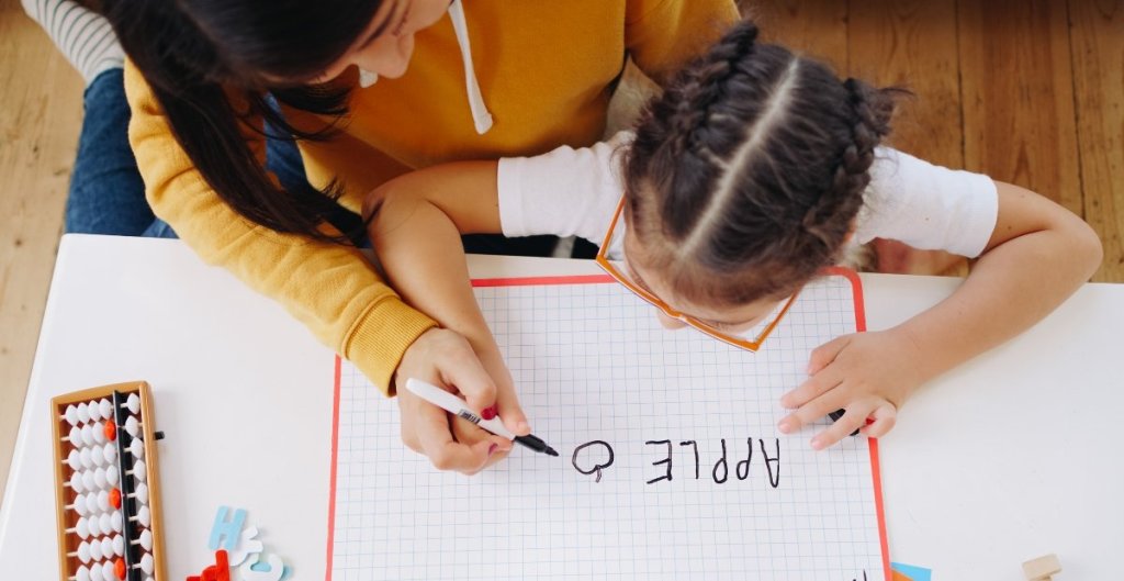mom helping her daughter draw an apple
