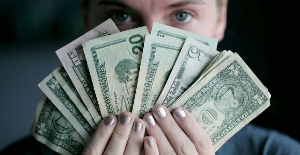 woman holding a bunch of cash bills fanned out