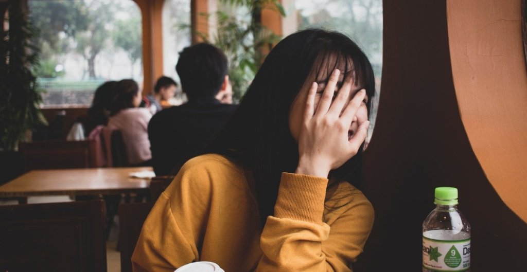woman in a restaurant covering her face with her hand