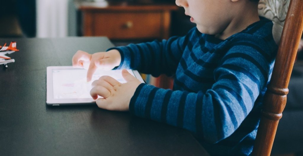 young child at a table with an ipad