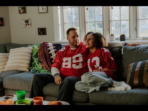 dad and daughter in football jerseys snuggled up on the sofa