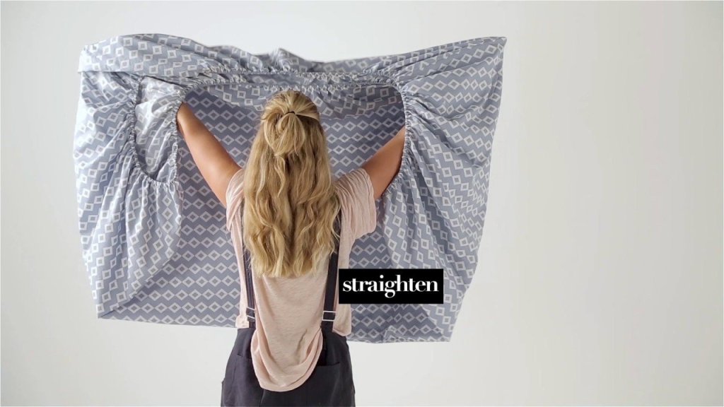 woman folding a fitted sheet