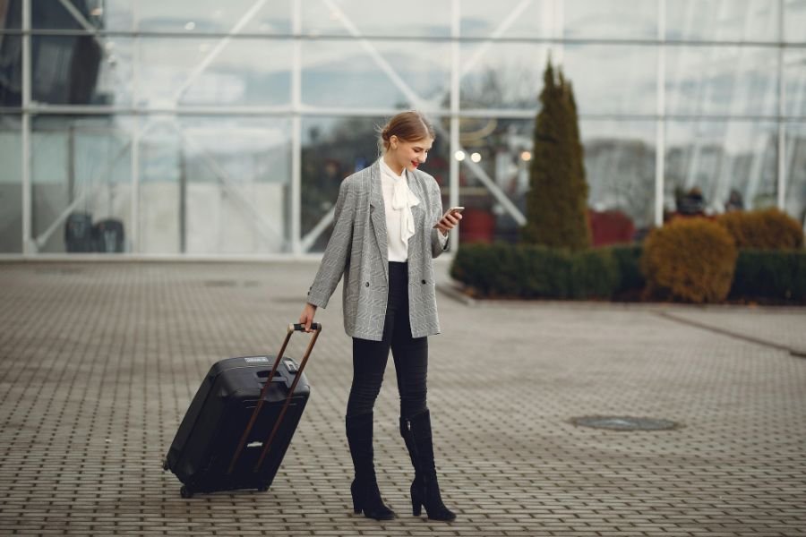 woman on phone pulling luggage