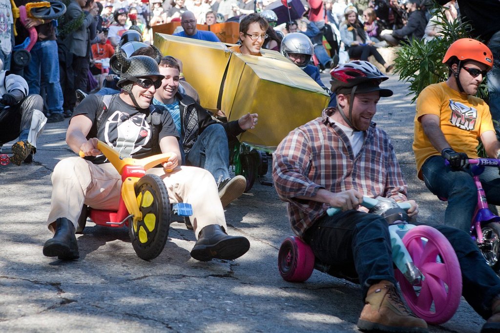 men riding Big Wheels