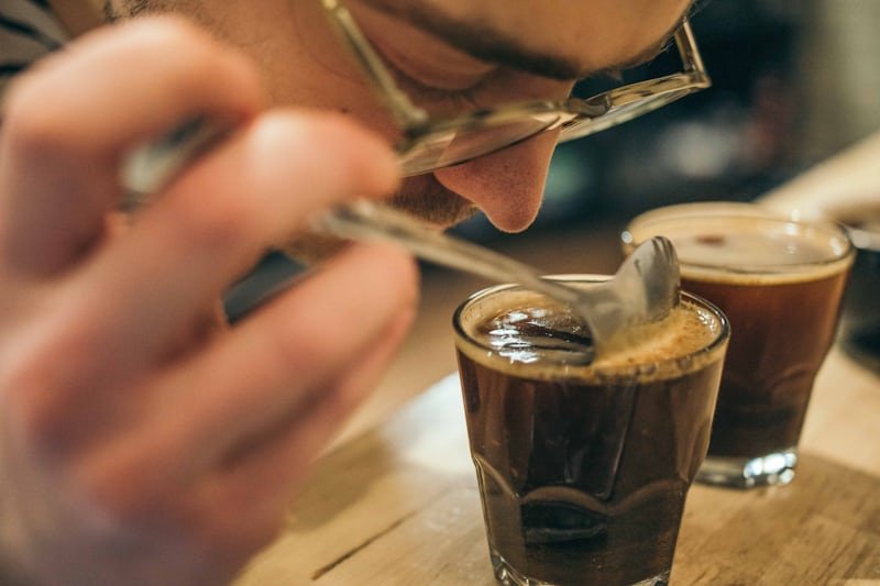 man smelling a shot of coffee