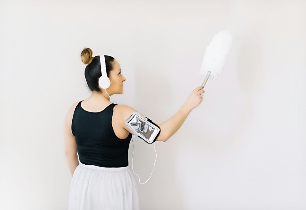 woman wearing headphones and carrying a duster