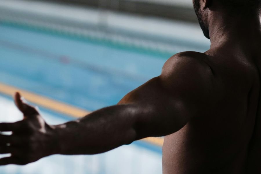 black male swimmer in front of a swimming pool