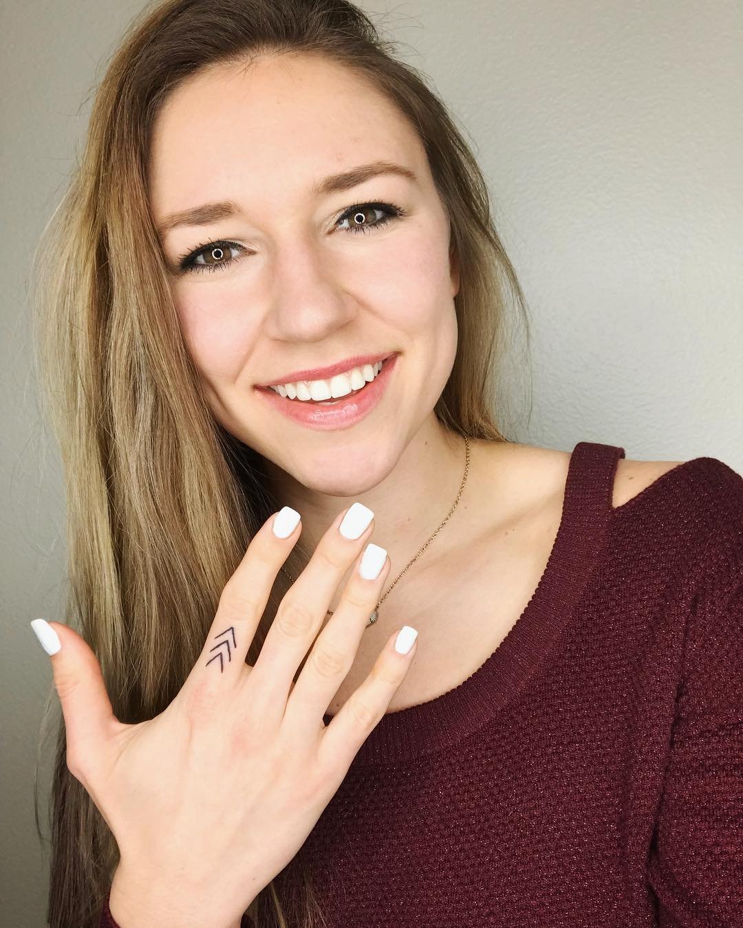 A woman displaying three arrow Lucky Few Tattoo on her finger
