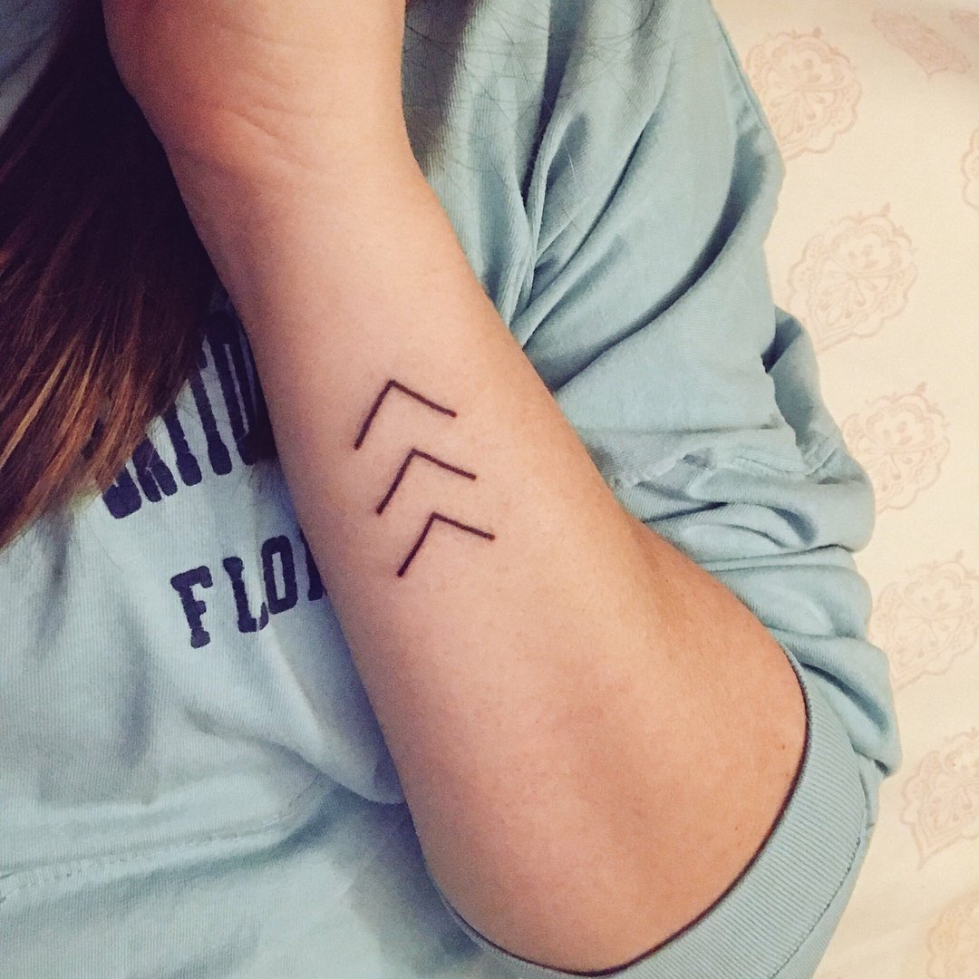 Woman displaying three arrow Lucky Few Tattoo on her forearm