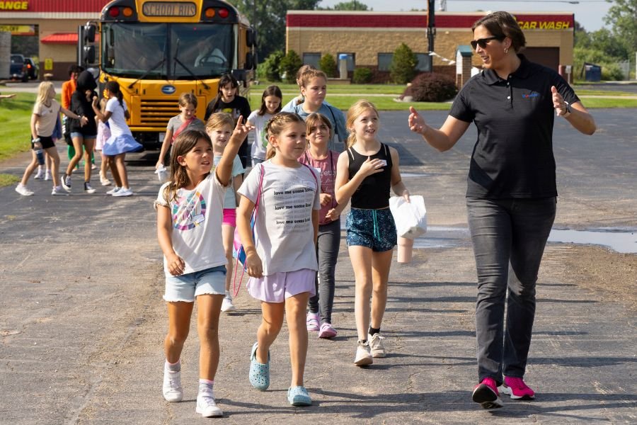 kids walking with an adult guide near a school bus