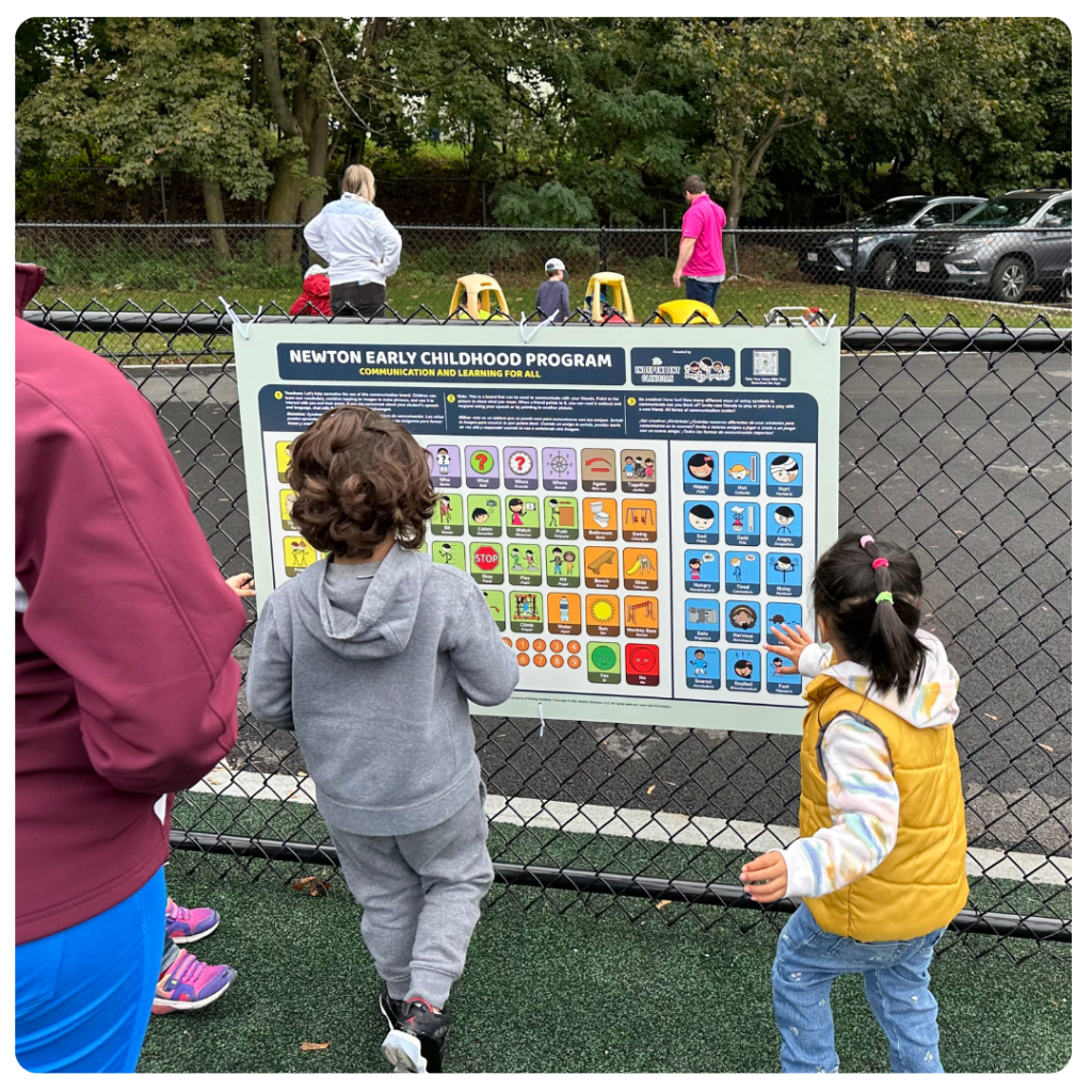 kids at a playground in front of a communication board