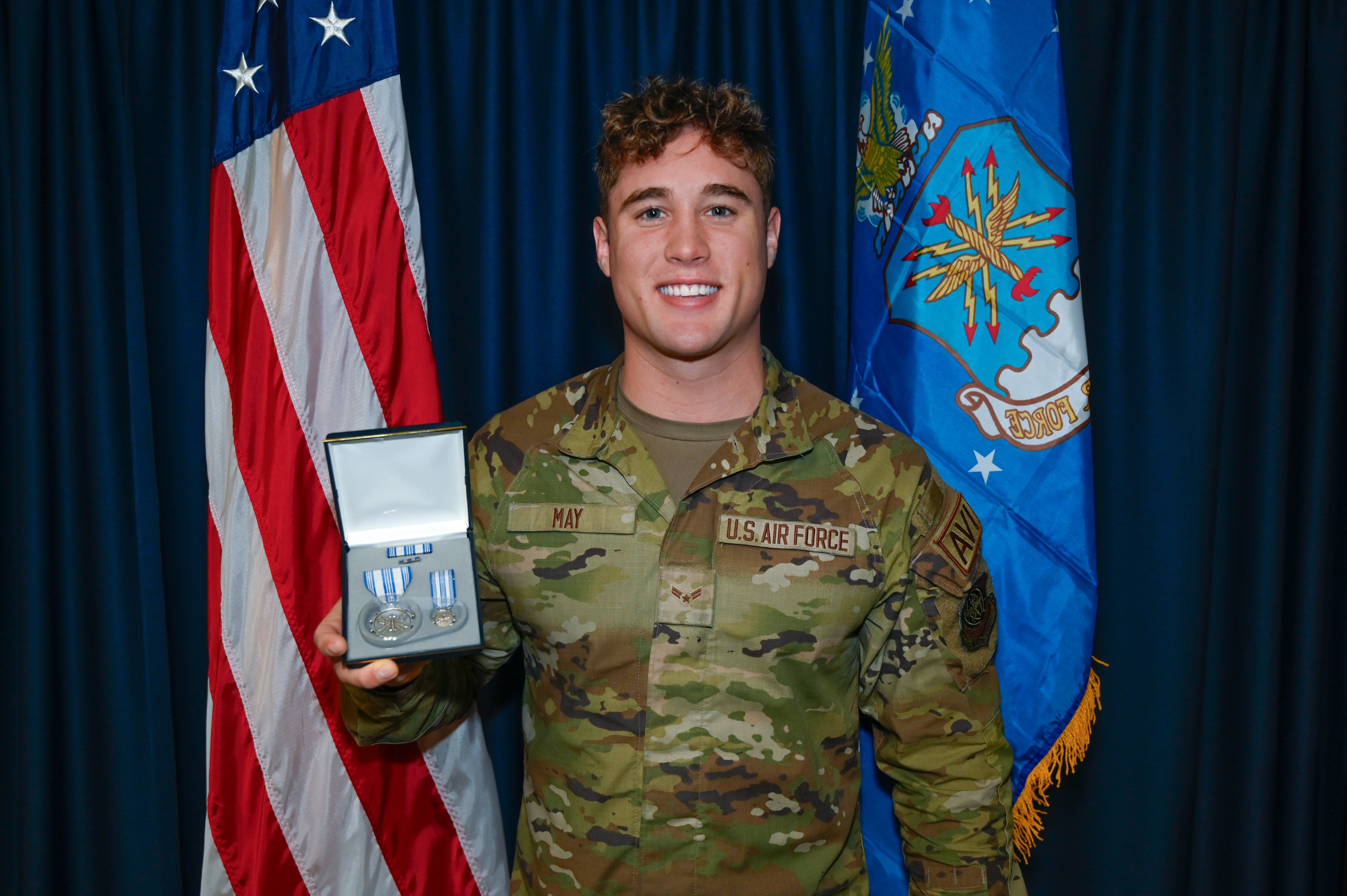 Air Force Airman Troy May holding achievement medal