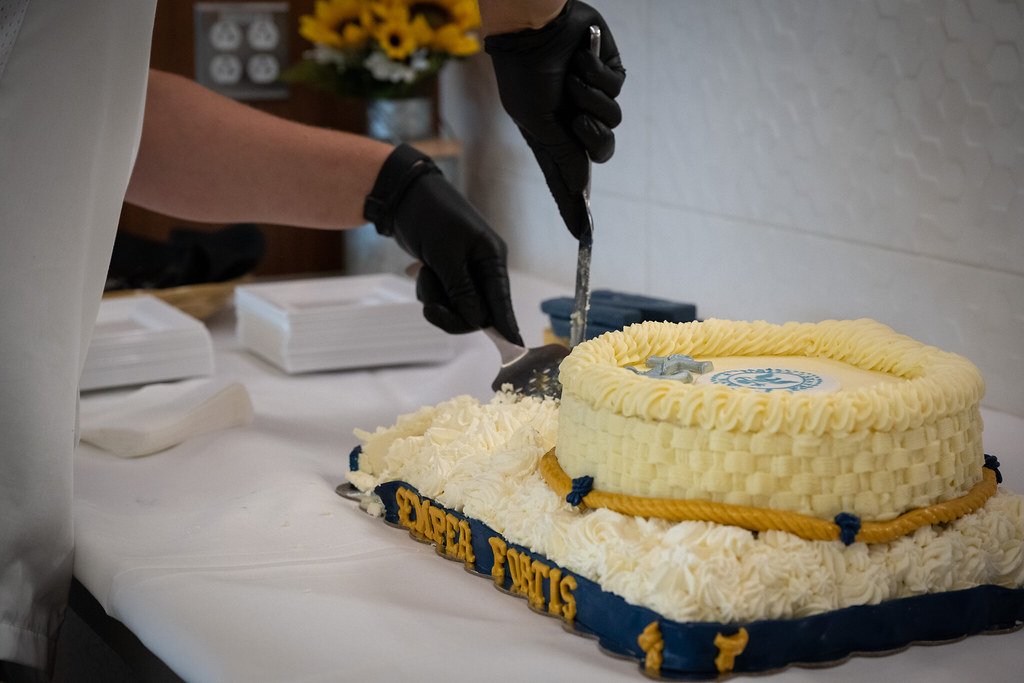 Person in gloves cutting a decorated cake with "Expert Pacts" on the side.