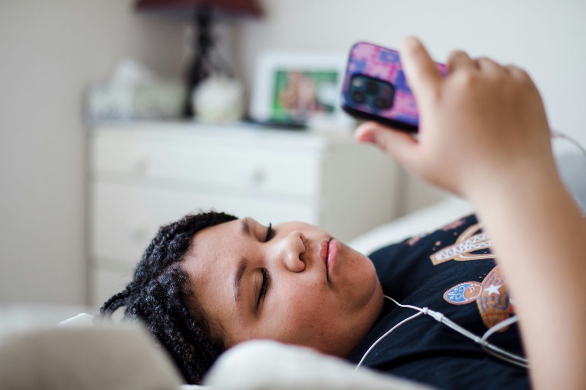 a girl laying in bed with a cell phone