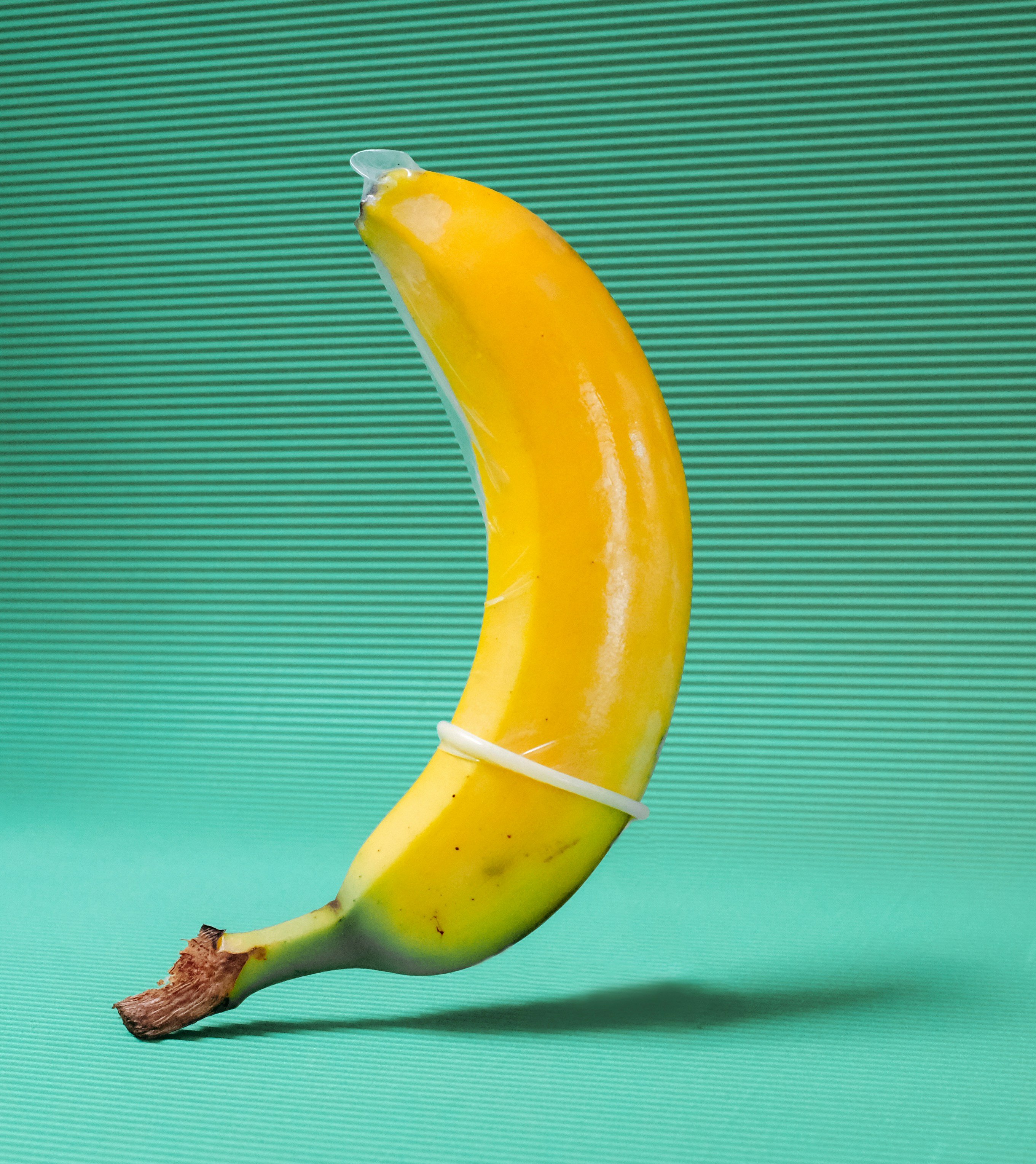 yellow banana fruit with condom on green textile