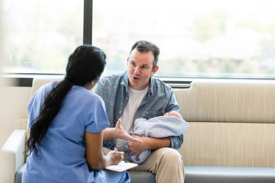man holding a baby talking to a doctor