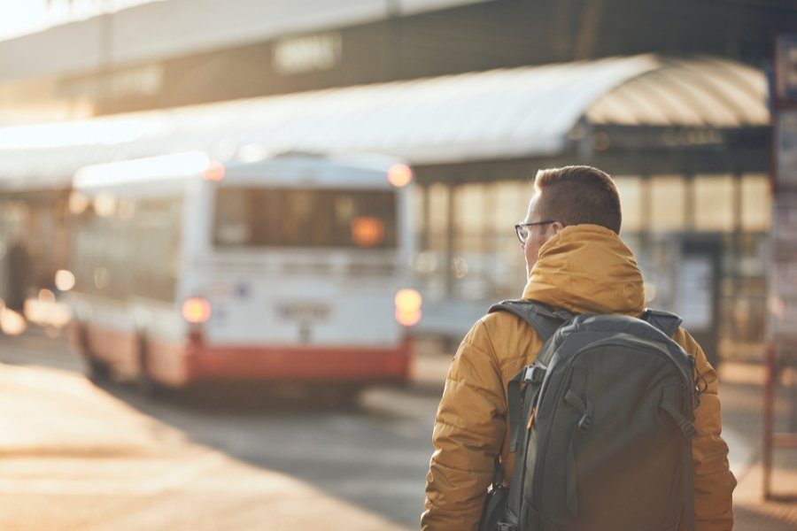 man walking alone behind a bus