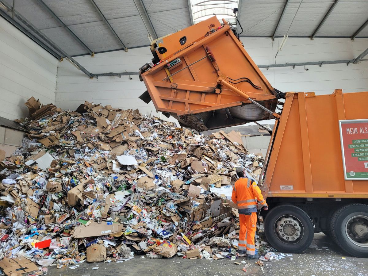 a garbage man standing next to a pile of trash