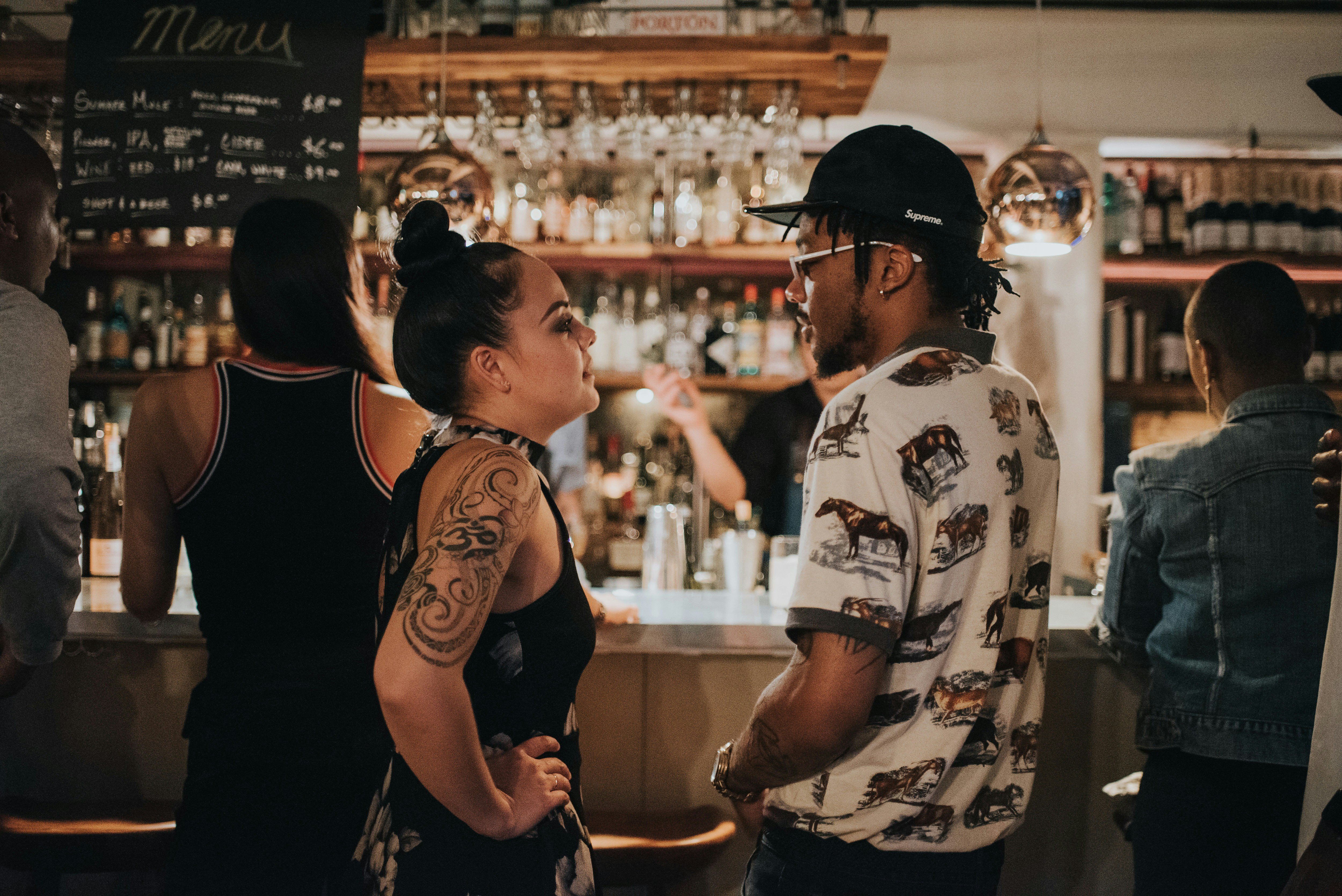 man and woman facing each other at a bar