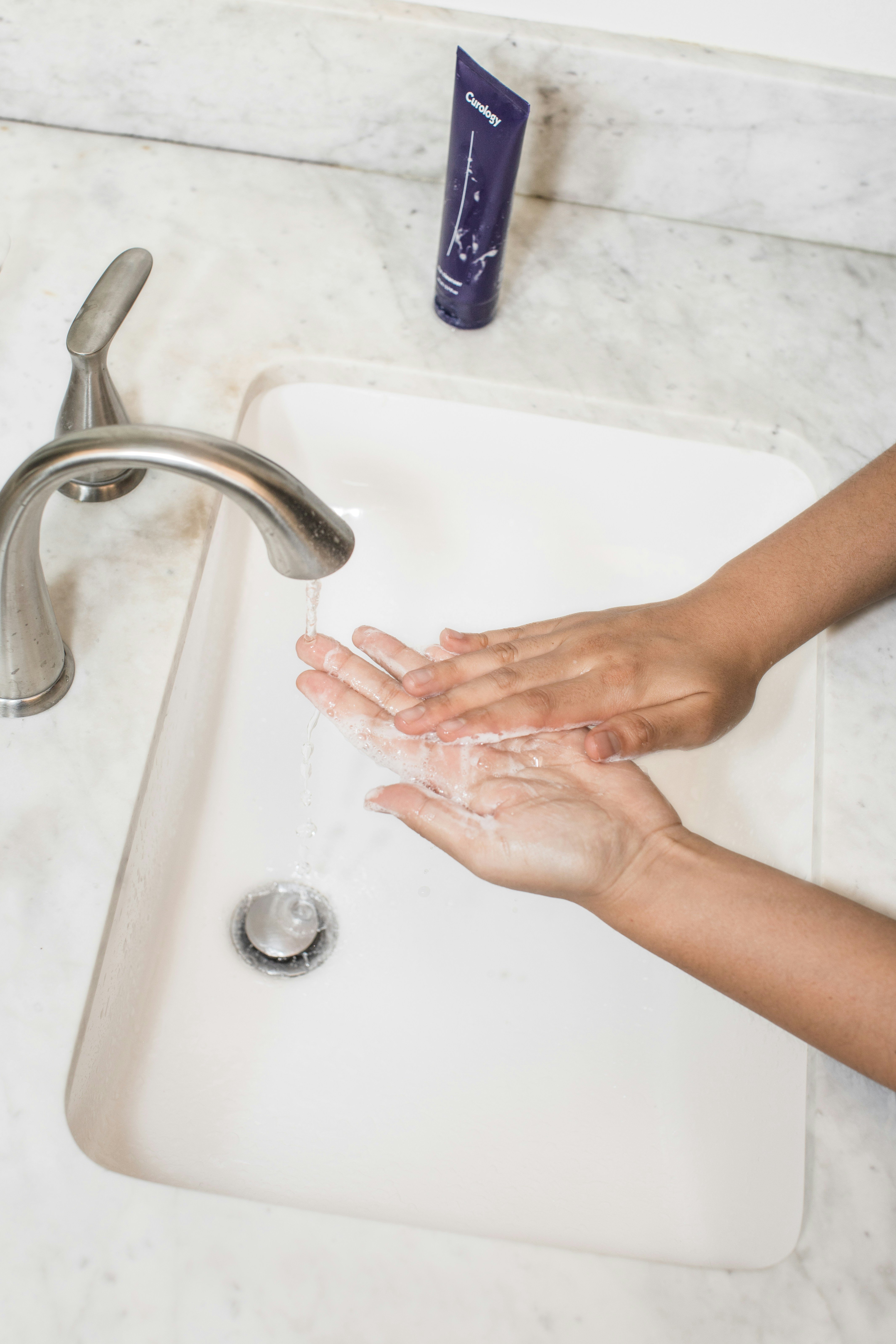 person washing hands in sink