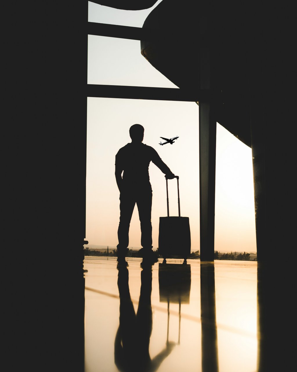 silhouette of a man holding luggage inside airport