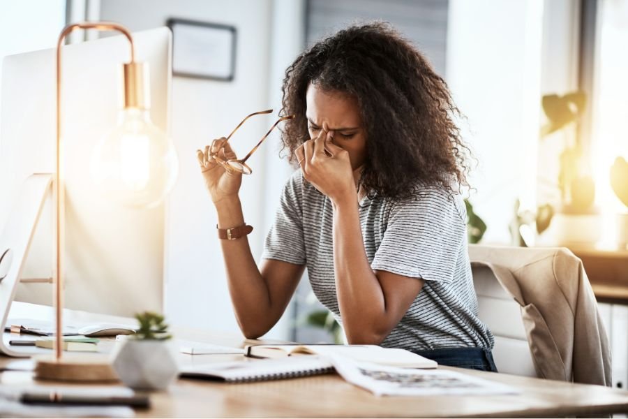 a curly-haired woman pinches the bridge of her nose