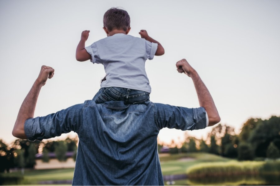 little boy on man's shoulders, flexing muscles