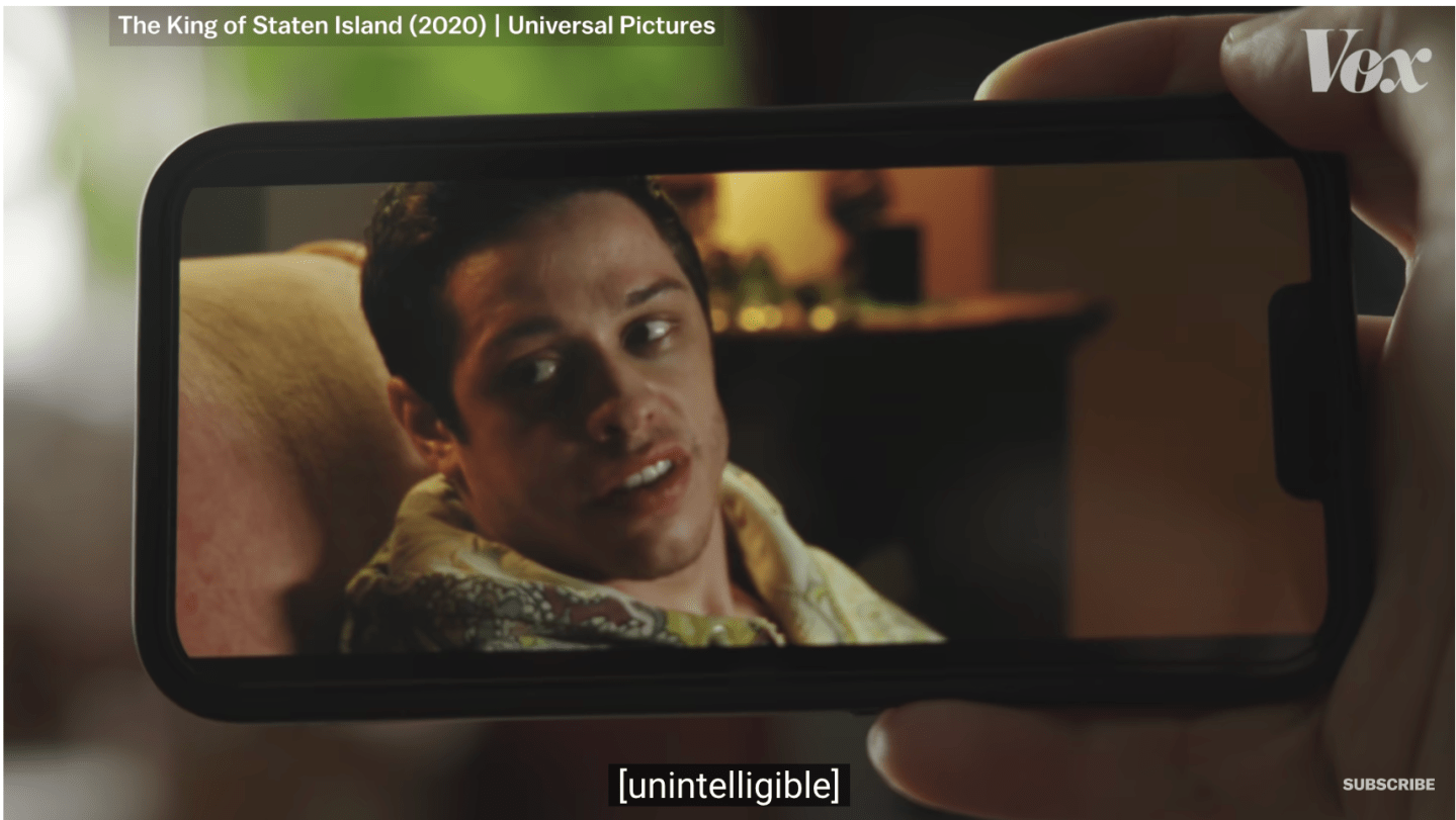 someone watching a video of Pete Davidson on their phone with subtitles at the bottom
