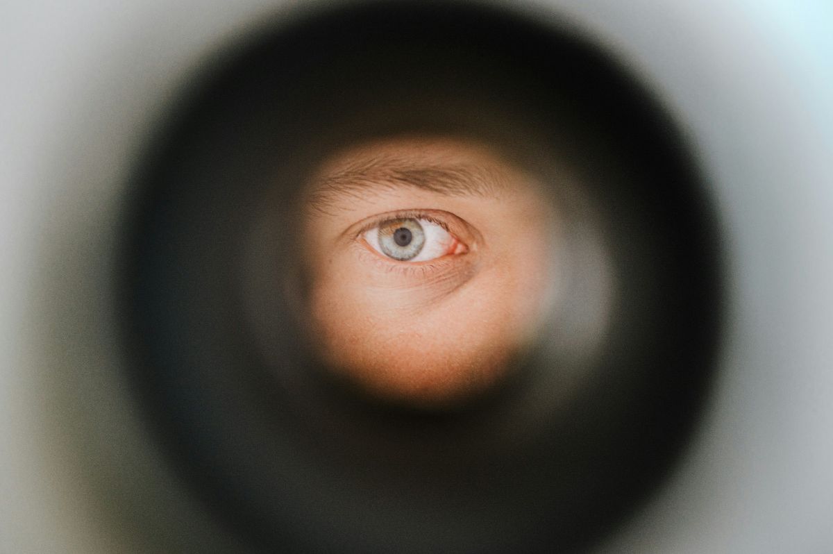 man's eye looking through peephole