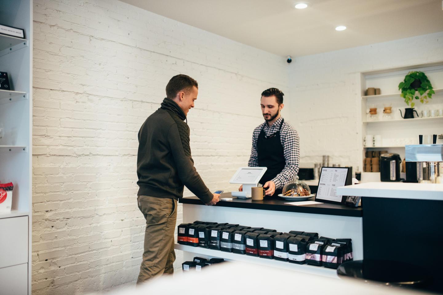 two men on either side of a counter completing a purchase