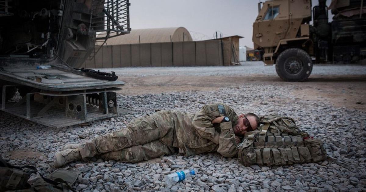 soldier in military uniform napping on the ground