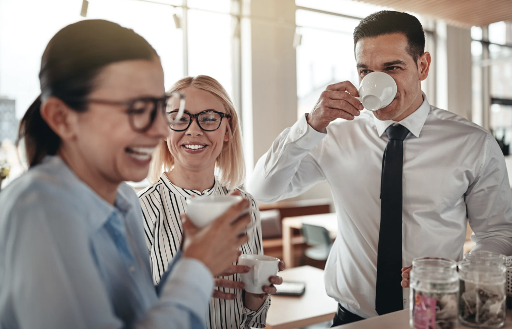 Three people drinking coffee and laughing