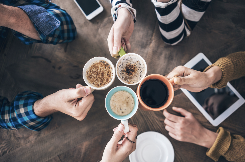 Hands hold coffee mugs, cheering