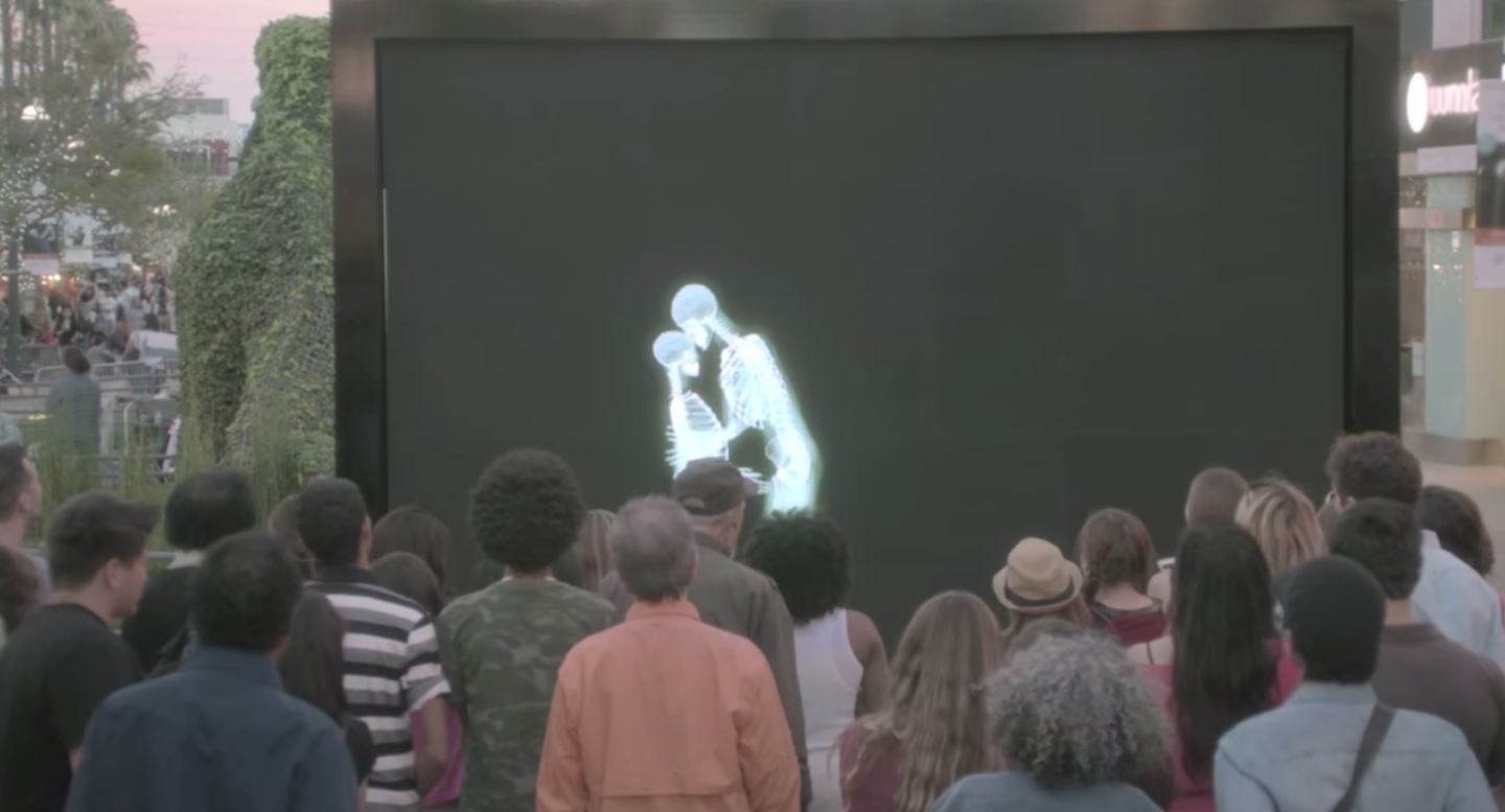 crowd watching embracing skeletons through screen