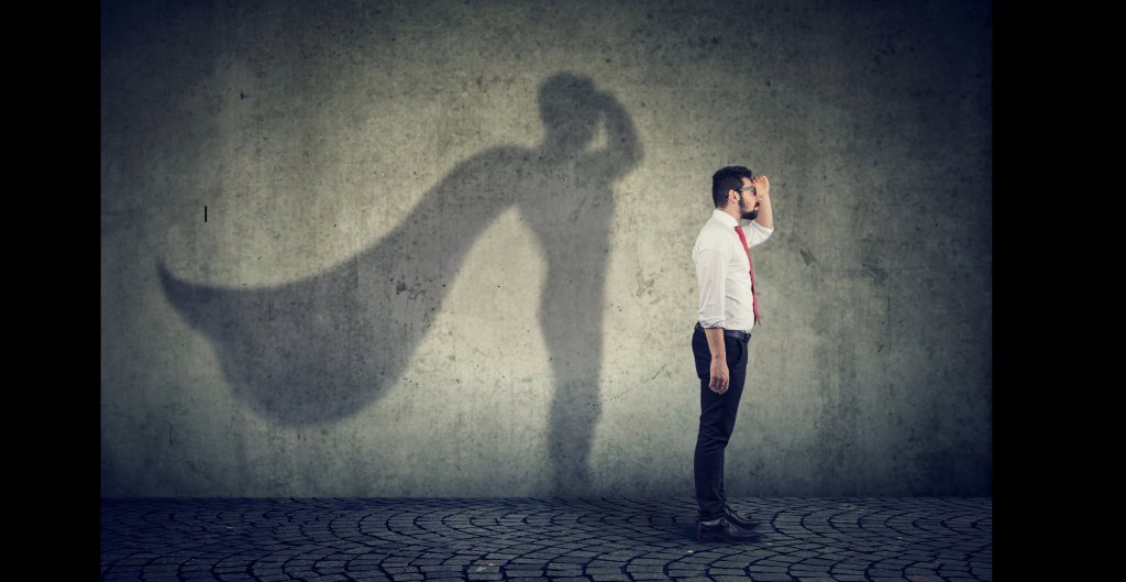 man standing with a caped hero shadow behind him
